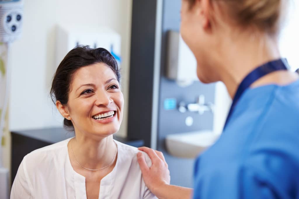 female patient sitting with a doctor in scrubs comforting her